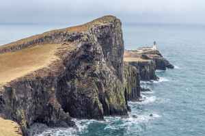 lighthouse on near body of water between rock formation