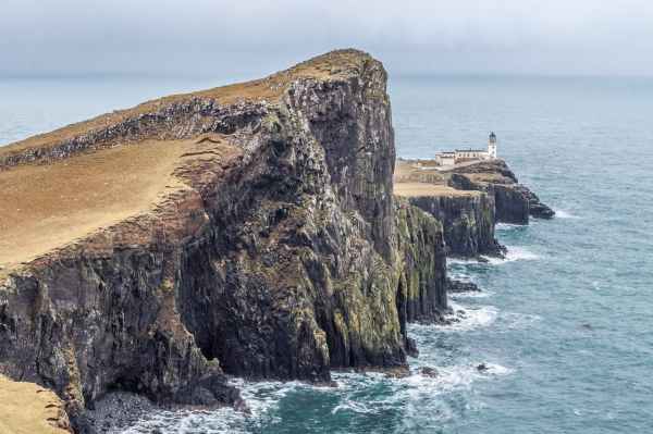 lighthouse on near body of water between rock formation